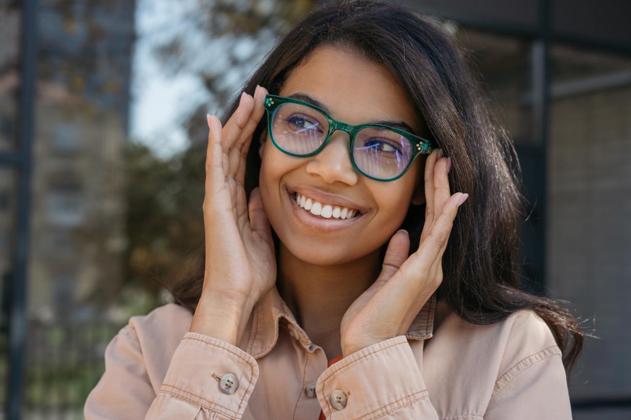 Happy girl in stylish spectacles posing for pictures outdoors
