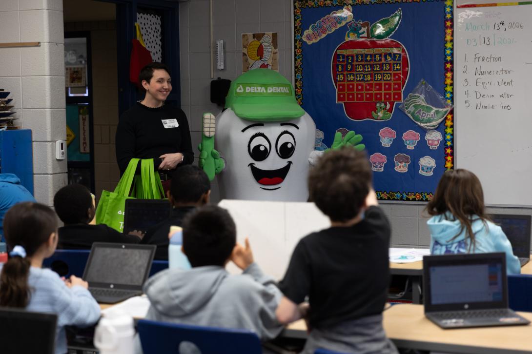 Happy Delta Dental employee volunteering in a classroom with Dazzle.